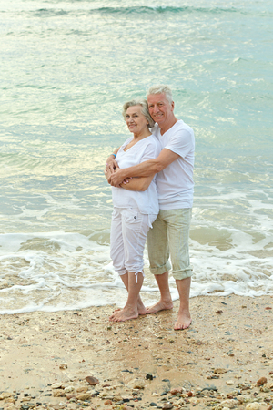 happy beautiful senior couple hugging on beachの写真素材
