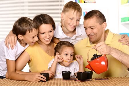 Family drinking tea at table in kitchen