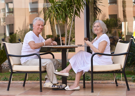 Nice senior couple with coffee sitting on the table on vacationの写真素材