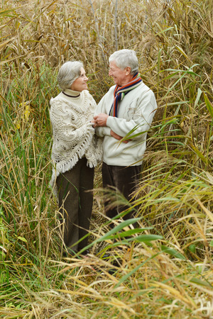Happy senior couple standing in autumn parkの写真素材