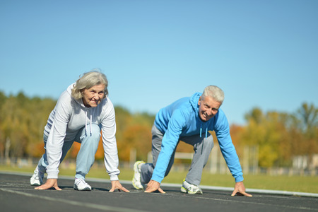 Happy fit senior couple jogging at stadiumの写真素材