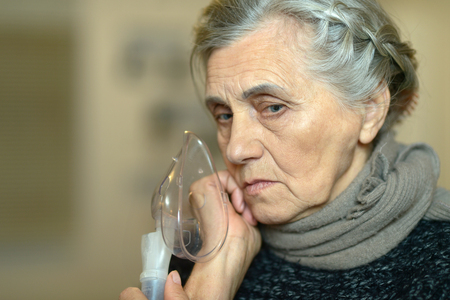 Senior woman making inhalation on dark backgroundの写真素材