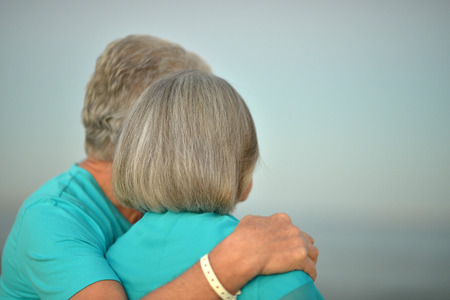 Happy Mature couple relaxing on beach,back viewの写真素材
