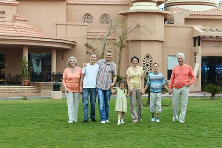 Happy family relaxing at vacation resort with hands up
