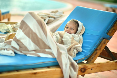 Little girl covered with towel near swimming poolの写真素材