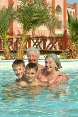 Happy grandparents with their grandchildren in pool on vacationの写真素材