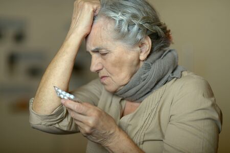 Sick senior woman with pills having a headachの写真素材