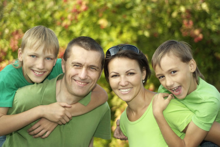 friendly family in green shirts walking in the summer parkの写真素材