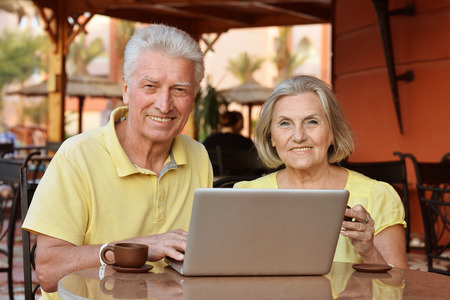 Mature couple sitting with laptop in hotel with teaの写真素材