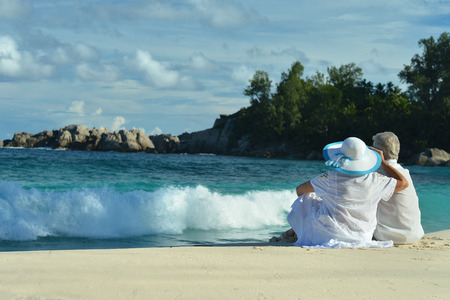 Elderly couple sitting on the shore and looks at seaの写真素材