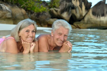 Elderly couple lying on the beach in the waterの写真素材