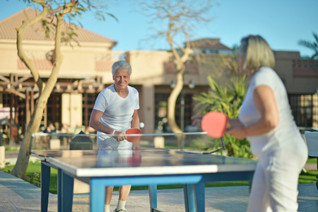 Elderly couple playing table tennis at hotel yardの写真素材