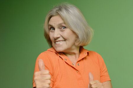 Portrait of a beautiful older woman on a green backgroundの写真素材