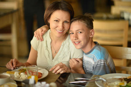 Happy mother and son at breakfast on the tableの写真素材
