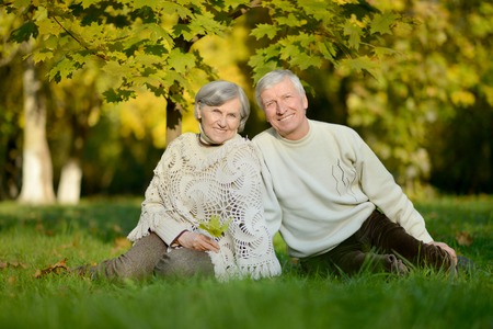Happy elderly couple sitting in autumn natureの写真素材