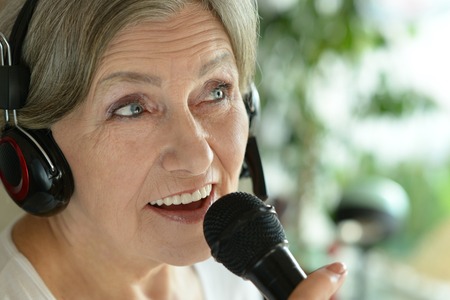 Portrait of a senior woman singing into microphoneの写真素材