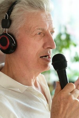 Senior man in headphones singing into microphoneの写真素材