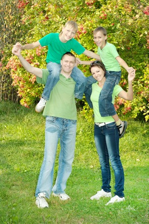 friendly family in green shirts walking in the summer parkの写真素材