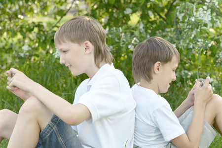 Two boys play a game on the phone outdoorsの写真素材