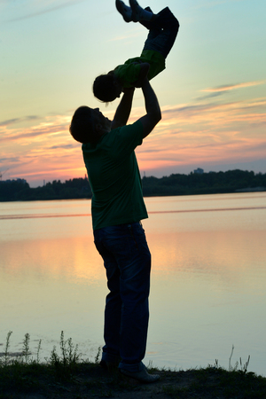 Father and son playing on the beach at the sunset timeの写真素材