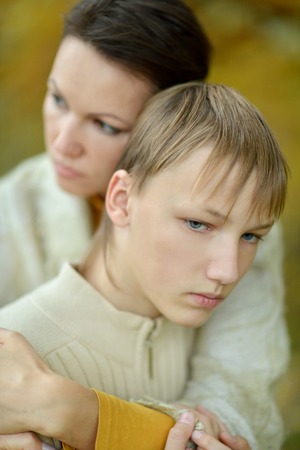 Sad mother with son on a walk in autumn parkの写真素材
