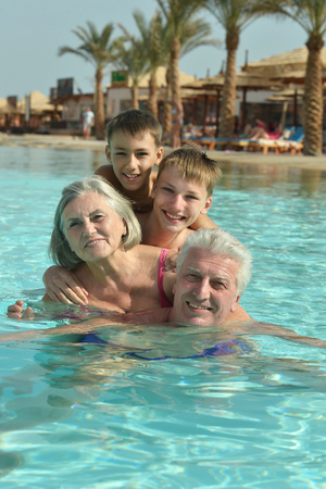 Happy grandparents with their grandchildren in pool on vacationの写真素材