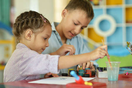 Little girl with boy drawing at homeの写真素材