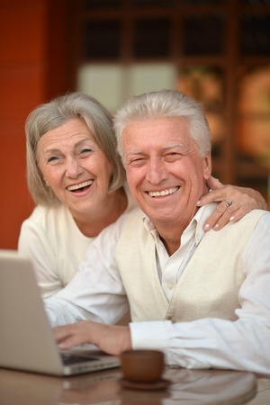 Mature couple sitting with laptop in hotel with teaの写真素材