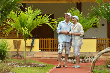 Happy elderly couple standing  in tropical garden outdoorの写真素材