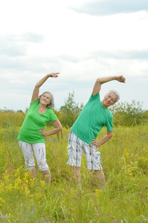 Happy fit senior couple exercising in summer parkの写真素材