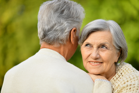 Happy senior couple relax in autumn park,woman pointing at somethingの写真素材