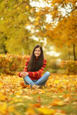 Beautiful girl with leaves in autumn parkの写真素材
