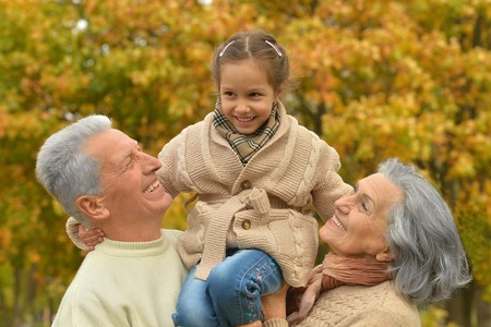 Grandparents with her granddaughter in the autumn parkの写真素材