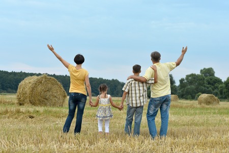Happy family in wheat field in sunny day,back viewの写真素材