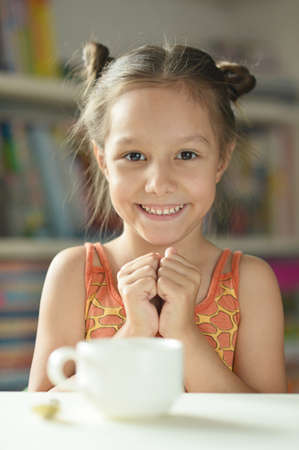 Cute little girl with cup  on the table