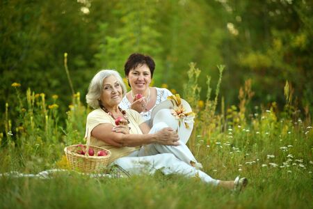 Happy elder women resting on grass at natureの写真素材