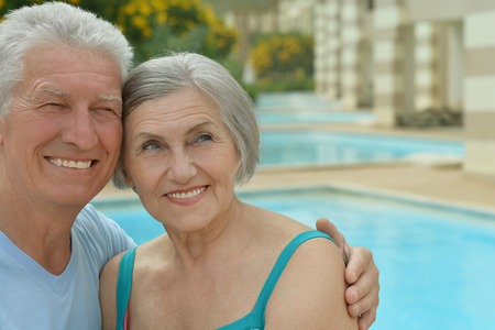Happy Elderly couple resting near pool water together at vacationの写真素材