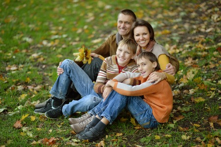 Portrait of a beautiful happy family sitting in autumn parkの写真素材
