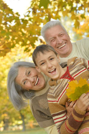 Happy smiling grandparents with their grandson in autumn forestの写真素材