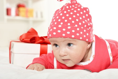 Adorable baby girl in red clothes with giftsの写真素材