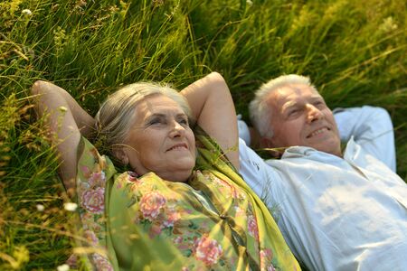 Happy senior couple lying on green grassの写真素材
