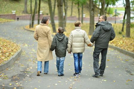 Happy family relaxing in autumn park,back view