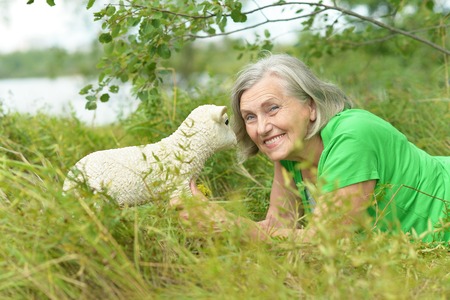 Senior woman with toy sheep on natureの写真素材