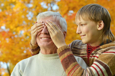 Grandfather with boy resting in autumn park