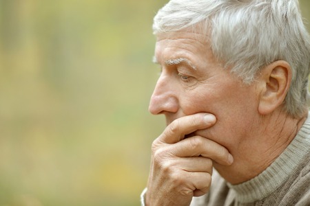 Portrait of thoughtful elderly man on yellow autumn background