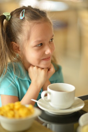 Cute little girl with cup on the tableの写真素材
