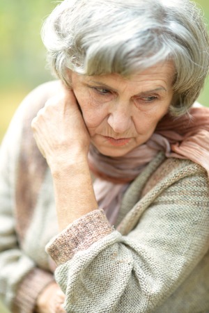 Portrait of thinking senior woman in autumn parkの写真素材