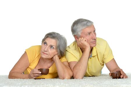 Portrait of an aged couple lying at floor with cupsの写真素材