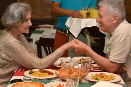 Happy mature couple eating dinner at restaurantの写真素材