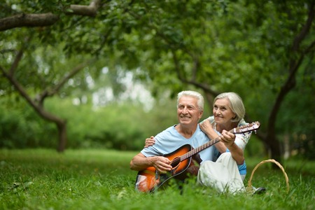 Loving mature couple with guitar   in summer park